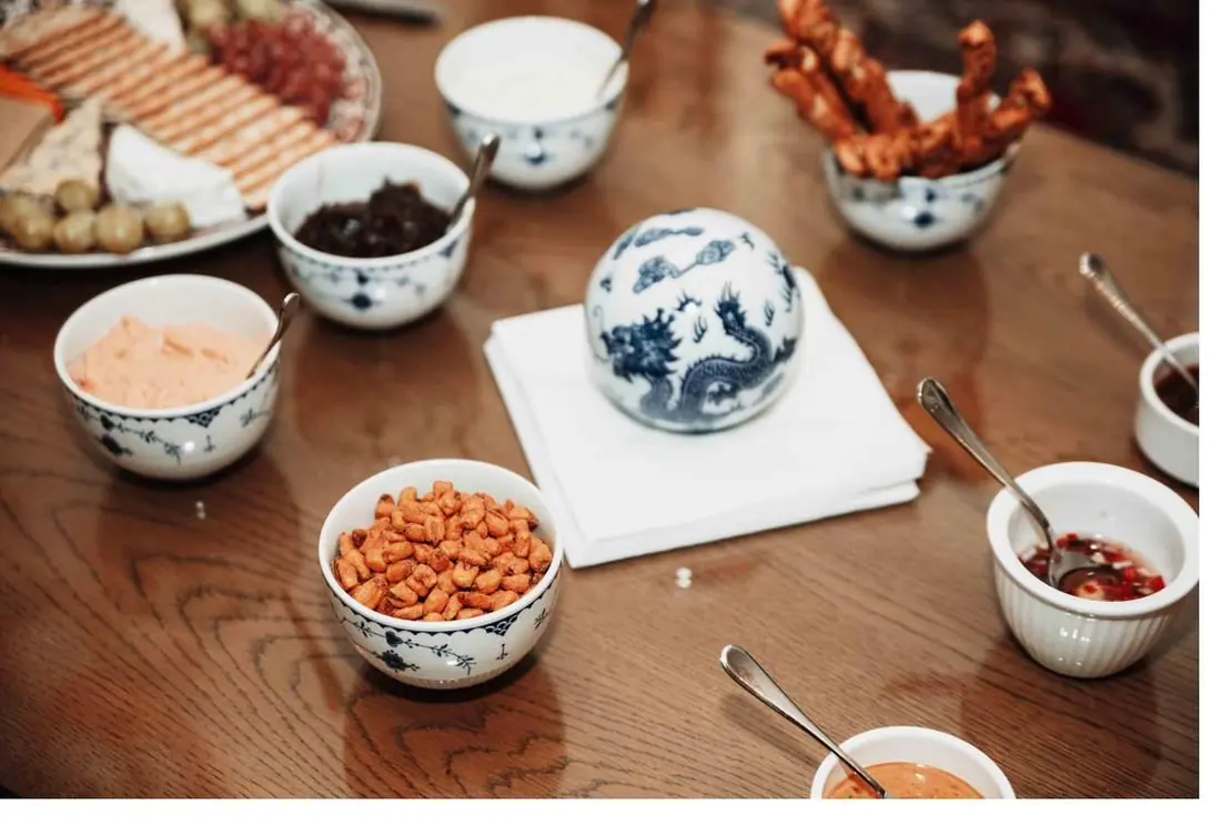Blue-and-white bowls of snacks and dips around a blue-and-white porcelain jar on a wooden table